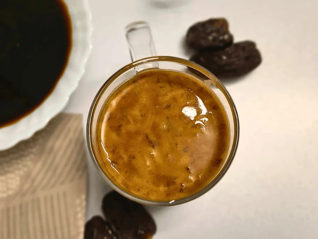 Overhead view of balsamic date vinaigrette in a glass surrounded by Medjool dates