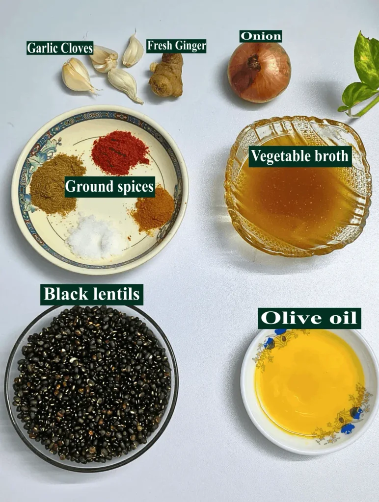 Ingredients for a black lentils recipe, including black lentils, onion, garlic, fresh ginger, and ground spices
