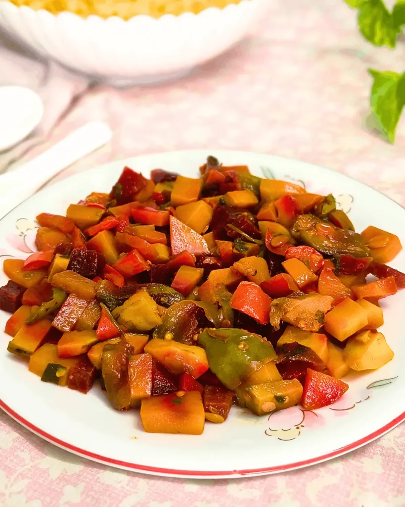 Plate of colorful diced CAVA-style roasted vegetables in orange, red, and green with rice behind it
